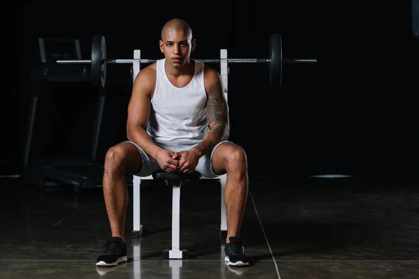 Seria afroamericana atleta masculino mirando cámara y sentado en el gimnasio - foto de stock