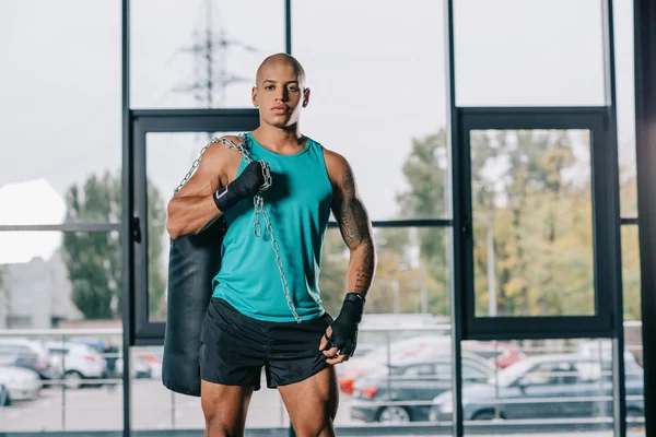 Confident african american male boxer standing with punching bag at gym — Stock Photo