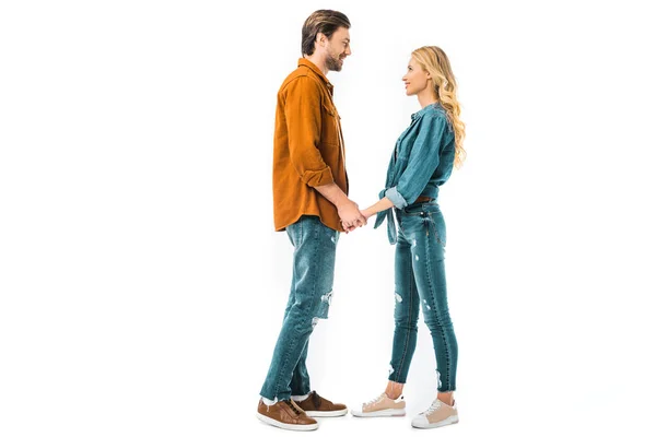 Vista lateral de pareja joven tomados de la mano y mirándose aislados en blanco — Stock Photo