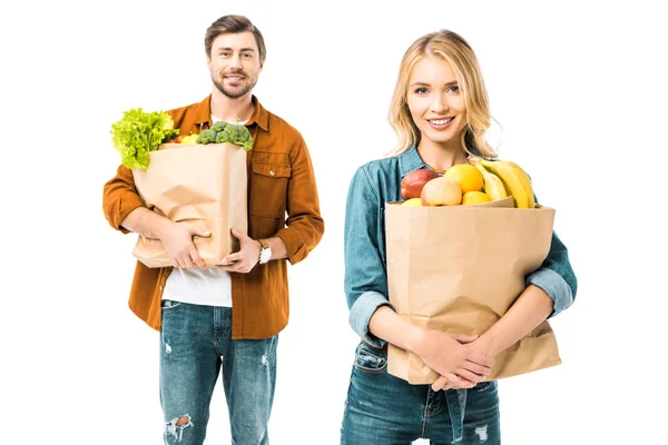 Bonita mujer joven sosteniendo bolsa de papel con comida mientras su novio de pie detrás aislado en blanco - foto de stock