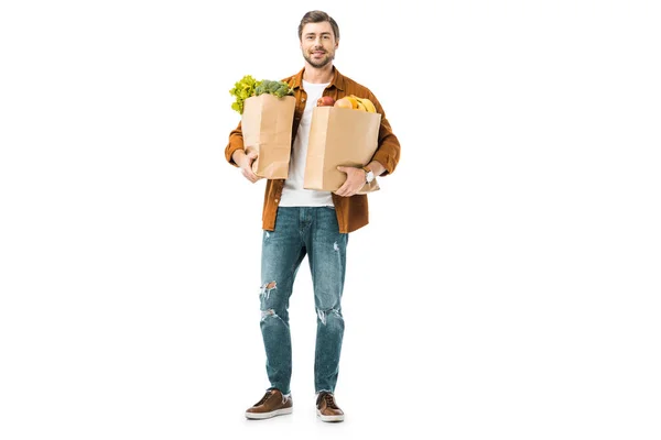 Joven sosteniendo bolsas llenas de productos aislados en blanco - foto de stock