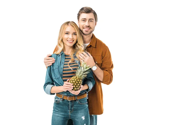 Uomo abbracciando fidanzata felice mentre lei tenendo ananas isolato su bianco — Foto stock