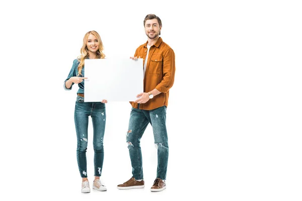 Alegre chica apuntando con el dedo en banner vacío mientras su novio de pie cerca aislado en blanco - foto de stock