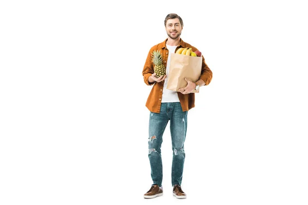 Man holding pineapple and paper bag full of products isolated on white — Stock Photo