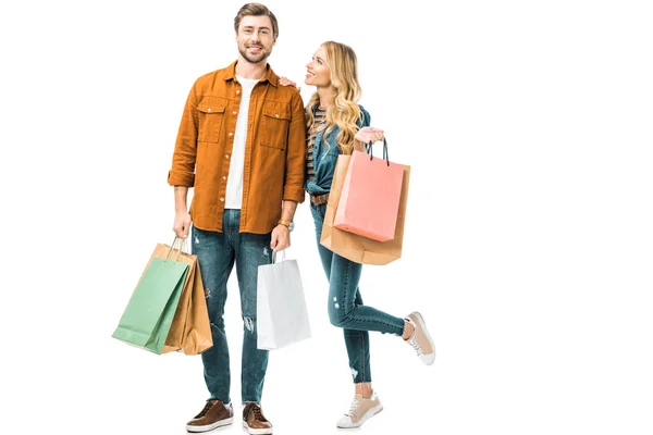 Feliz jovem casal segurando sacos de compras coloridos isolados no branco — Fotografia de Stock