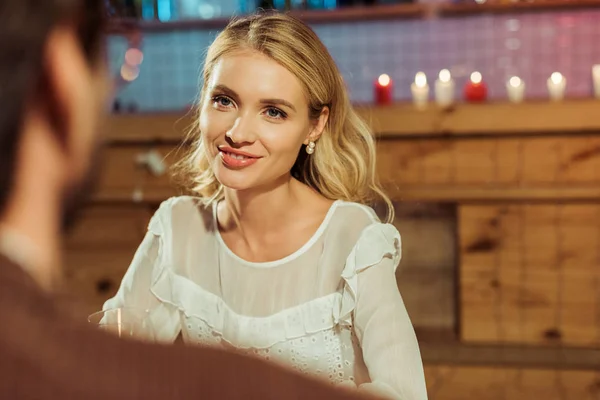Избирательный фокус улыбающейся красивой женщины, встречающейся с парнем в ресторане — стоковое фото