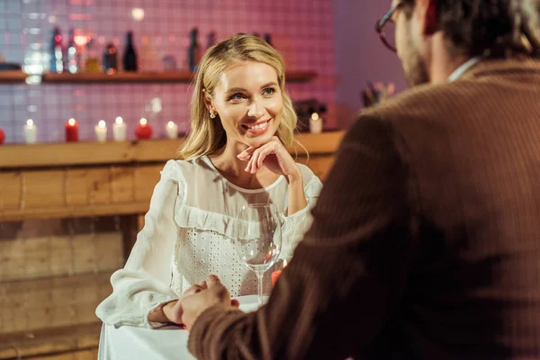 Attractive happy woman having date and holding hands with boyfriend at restaurant — Stock Photo