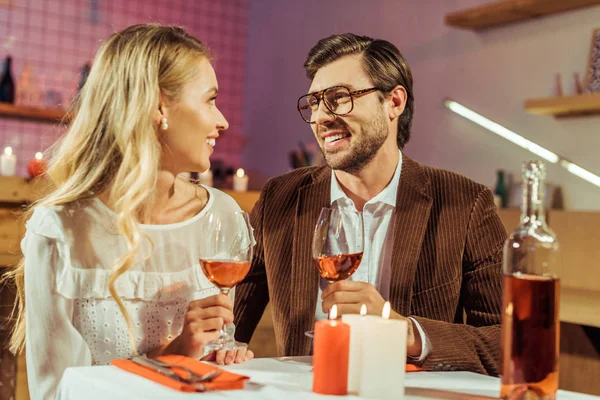 Couple with wine glasses celebrating and having date at table with candles in restaurant — Stock Photo