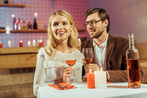 Jovem casal com copos de vinho comemorando e tendo data à mesa com velas no restaurante — Fotografia de Stock