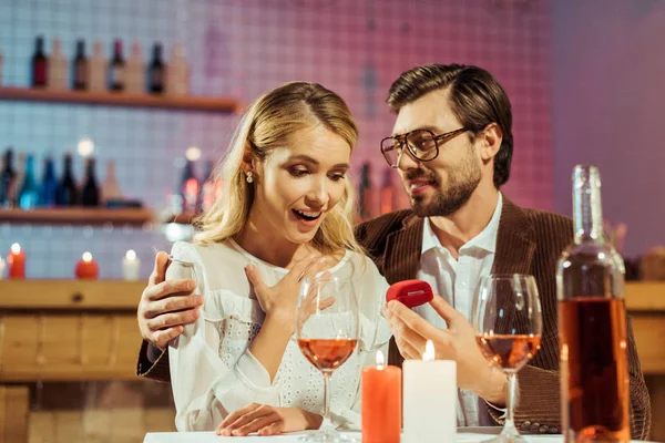 Glücklicher junger Mann macht seiner schönen Freundin während eines romantischen Abendessens im Café einen Heiratsantrag — Stockfoto