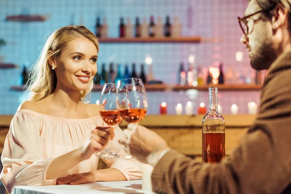 Pareja celebrando y tintineo por copas de vino en la mesa en el restaurante - foto de stock