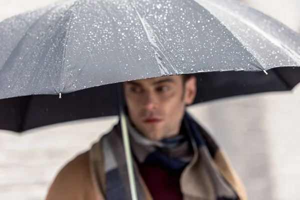 Homem bonito de casaco e cachecol com guarda-chuva de pé na rua — Fotografia de Stock