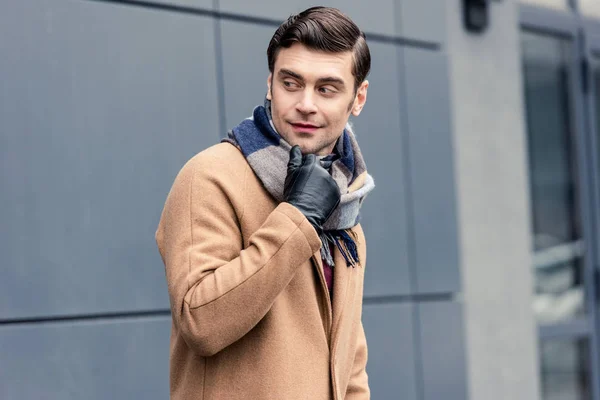 Handsome man in coat and scarf looking away on street — Stock Photo