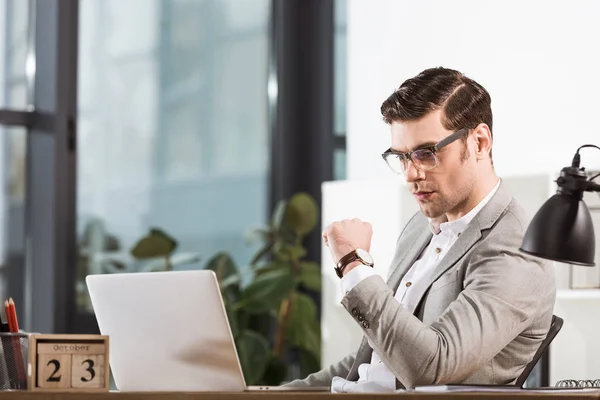Bel homme d'affaires réfléchi travaillant avec ordinateur portable au bureau moderne — Photo de stock