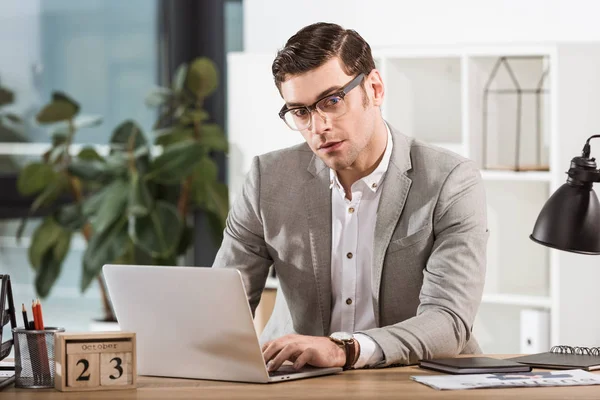 Homem de negócios elegante bonito que trabalha com laptop no escritório — Fotografia de Stock