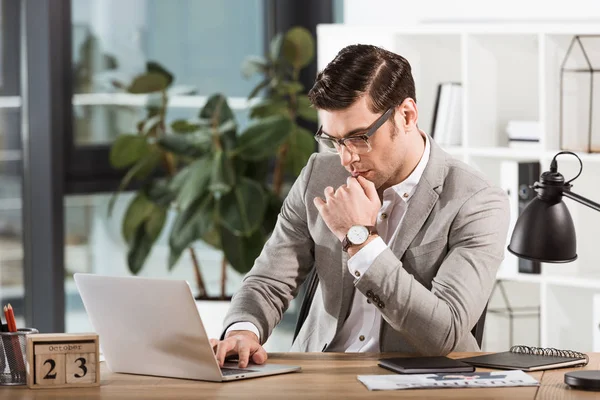 Gutaussehender fokussierter Geschäftsmann, der im Büro mit Laptop arbeitet — Stockfoto