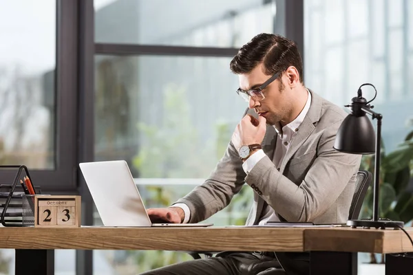 Gutaussehender, konzentrierter Geschäftsmann, der im Büro mit Laptop arbeitet — Stockfoto