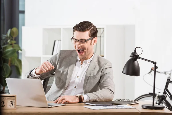 Handsome successful businessman celebrating victory at workplace — Stock Photo
