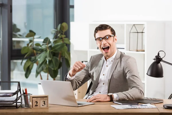 Bell'uomo d'affari di successo che celebra la vittoria sul posto di lavoro e guarda la fotocamera — Foto stock