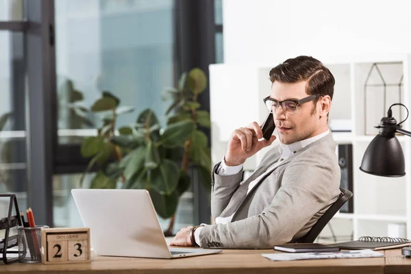 Successful confident businessman talking by phone at workplace in office — Stock Photo