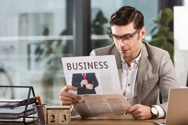 Schöner Geschäftsmann liest Zeitung am Arbeitsplatz im Büro — Stockfoto