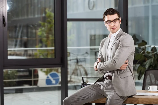 Handsome businessman sitting on workplace at office and looking away — Stock Photo