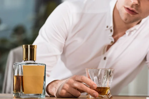 Cropped shot of drunk businessman holding glass of whiskey at office — Stock Photo