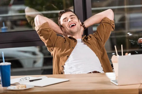 Schöner glücklicher Geschäftsmann entspannt sich an seinem Arbeitsplatz im Büro — Stockfoto