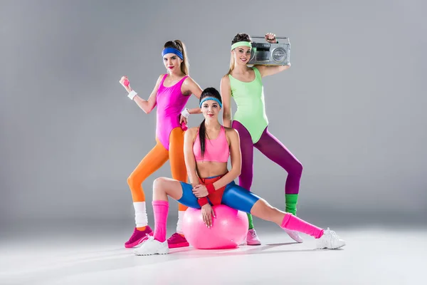 Chicas deportivas felices con equipo deportivo y grabadora en gris - foto de stock