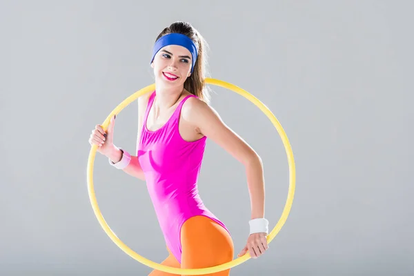 Entrenamiento de chica deportiva sonriente con hula hoop aislado en gris - foto de stock