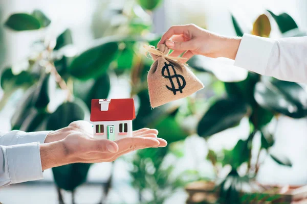 Vista parziale di persone che scambiano sacco borsa con segno di dollaro e modello di casa — Foto stock