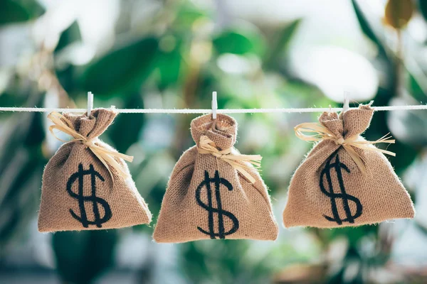 Sackcloth bags with dollar sign hanging on rope — Stock Photo