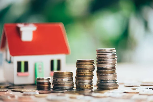 Close-up view of stacked coins and house model, savings concept — Stock Photo