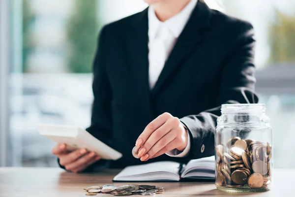 Cropped shot of businesswoman working and putting coin on pile — Stock Photo