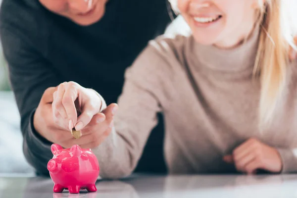 Schnappschuss von glücklichem Paar, das Münze in rosa Sparschwein steckt — Stockfoto
