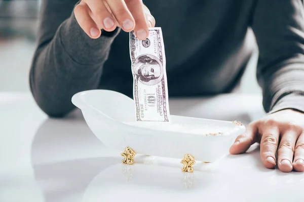 Partial view of man washing dollar banknote in small bathtub, money laundering concept — Stock Photo