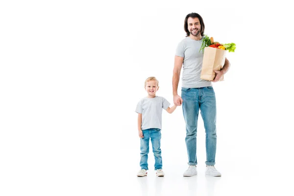 Padre e hijo después de comprar con bolsa llena de comida aislada en blanco - foto de stock