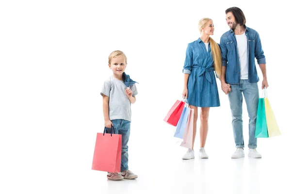 Hijo sosteniendo bolsa después de ir de compras y mirando a la cámara, los padres de pie detrás aislado en blanco - foto de stock