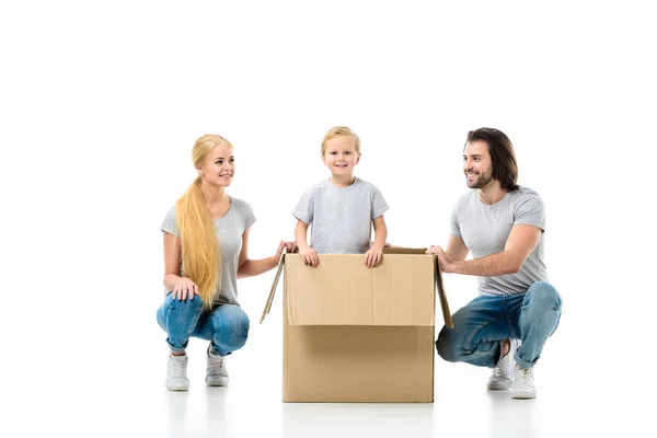 Familia feliz con hijo pequeño en una gran caja de papel móvil aislada en blanco - foto de stock