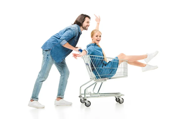 Pareja feliz divirtiéndose con carrito de compras aislado en blanco - foto de stock