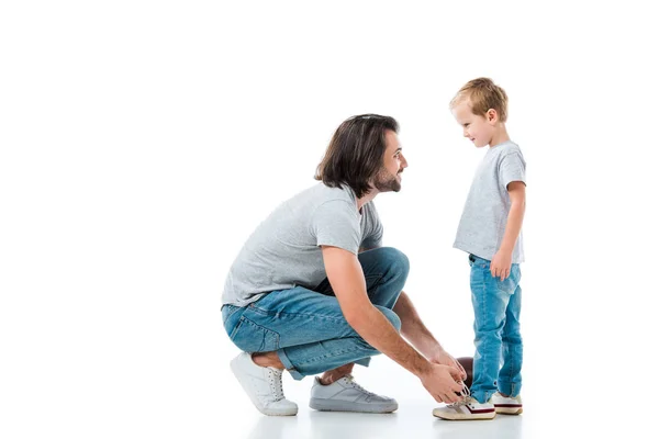 Pai carinhoso ajudando seu filho a amarrar cadarço isolado em branco — Fotografia de Stock