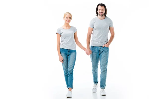 Lovely couple in grey t-shirts holding hands and smiling at camera isolated on white — Stock Photo