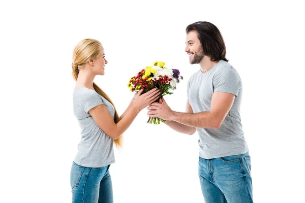 Schönes Paar, das einander ansieht und schöne Blumen auf weißem Grund hält — Stockfoto