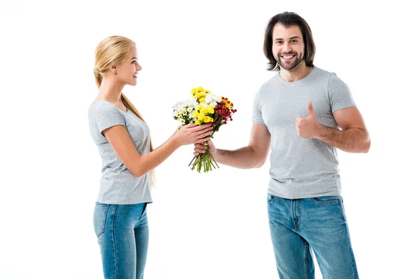 Beautiful couple, man holding flowers and pointing thumb up isolated on white — Stock Photo