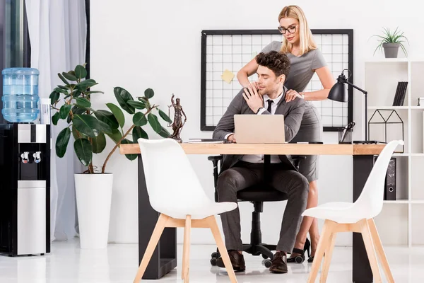 Бизнесвумен делает массаж коллеге на рабочем месте в офисе, концепция офисного романа — стоковое фото