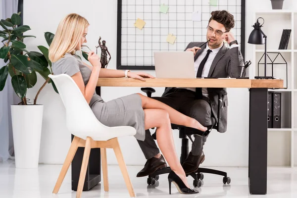 Jovem empresária flertando com colega de negócios no local de trabalho com laptop no escritório — Fotografia de Stock
