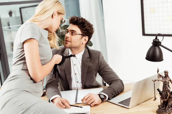 Businesswoman holding colleagues tie while flirting at workplace in office — Stock Photo