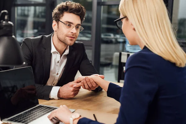 Young businesspeople holding hands while flirting at workplace, office romance concept — Stock Photo