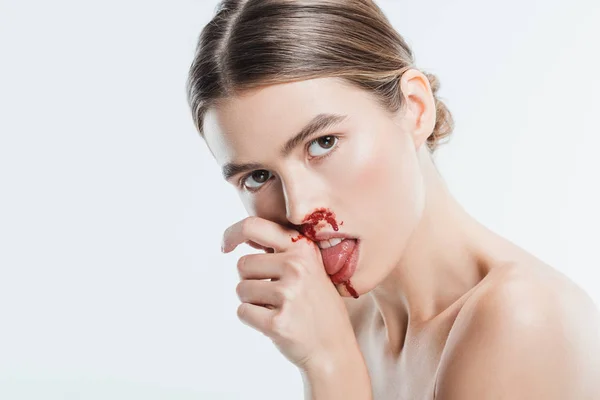 Обнаженная женщина с травмой на лице, облизывающая кровь из руки, изолированная на белом — стоковое фото