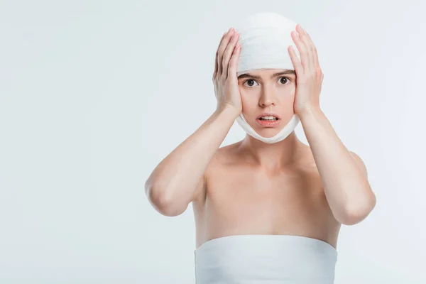 Femme adulte avec des bandages blancs tenant la tête avec les mains isolées sur blanc — Photo de stock